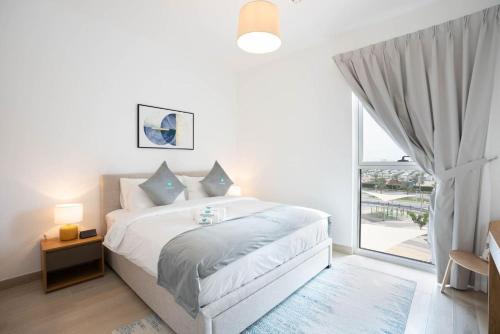ein weißes Schlafzimmer mit einem Bett und einem großen Fenster in der Unterkunft Bloomfields Iconic 1br Waters Edge Yas Island in Abu Dhabi