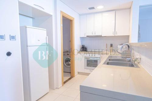a white kitchen with a sink and a refrigerator at Bloomfields Adorable 1br In Raha Beach Access in Abu Dhabi