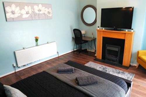 a living room with a television and a fireplace at Detached Homestay - Super, King & Double Rooms - Leyland, Preston, Chorley, Lancashire in Leyland