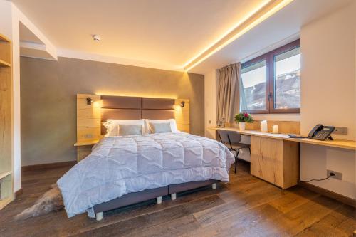 a bedroom with a bed and a desk and a desk at Riserva Bianca Limone Hotel & SPA in Limone Piemonte