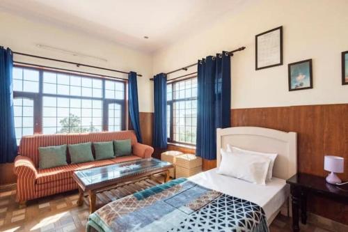 een slaapkamer met een bed en een bank bij Deodar Cottage - 3BHK Villa by DeodarStays in Mussoorie