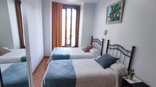 a hotel room with two beds and a mirror at Pension Segura in Murcia
