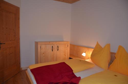a small room with a bed with yellow pillows at Pension zum Schreiner in Hermagor