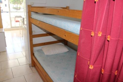 - deux lits superposés dans une chambre dotée de rideaux rouges dans l'établissement Appartement 2 pièces cabine - GRUISSAN GN400-013, à Gruissan