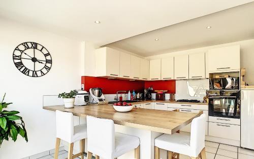 une cuisine avec une table en bois et des armoires blanches dans l'établissement Chambre privée chez l'habitant - La Chambre Framboise, à Colomiers