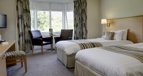 a hotel room with two beds and a table and chairs at Best Western The Dartmouth Hotel, Golf & Spa in Dartmouth