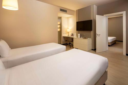 a hotel room with two beds and a desk at Best Western Plus Tower Hotel Bologna in Bologna