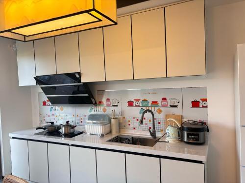 a kitchen with white cabinets and a sink at Shiguanghui in Sanya
