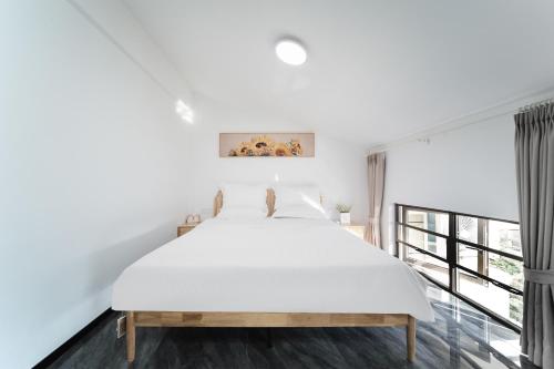 a white bedroom with a bed and a large window at Shiguanghui in Sanya