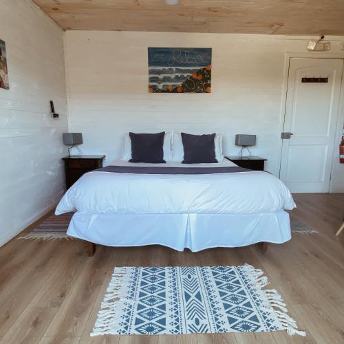 a bedroom with a large white bed with two lamps at Pichilemu Apart Hotel in Pichilemu