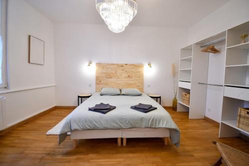 een grote witte slaapkamer met een bed en een kroonluchter bij Suite Belleville in Saint-Dizier