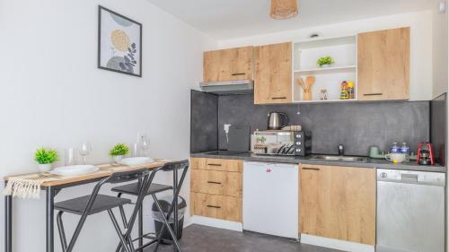 une cuisine avec des armoires en bois et un comptoir dans l'établissement Cosy studio avec terrasse et parking privé gratuit, idéal pour explorer Lyon, à Villeurbanne