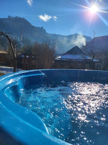a blue swimming pool with the sun in the background at Pensiunea Perla Durau in Durău