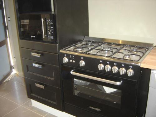 a kitchen with a black stove and a microwave at beautiful cottage with pool: 8 pers in Isolabona