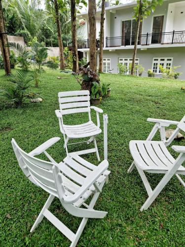 three white chairs sitting in the grass in front of a house at Villa Sole in Kandy