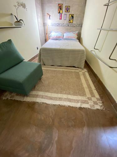 a bedroom with a bed and a green couch at Casa Maria trilheira in Petrópolis