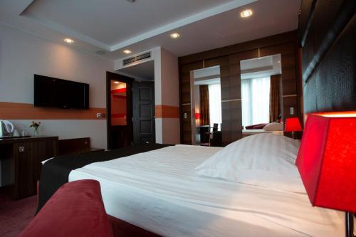 a bedroom with a large white bed with a flat screen tv at Art Hotel William in Bratislava