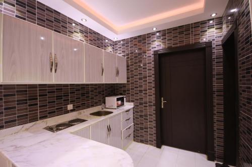 a kitchen with white cabinets and a black door at Beautiful Moment Furnished Apartments in Riyadh
