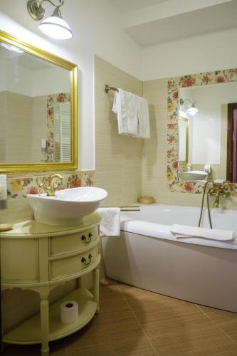 a bathroom with a sink and a tub and a mirror at Pensiunea Casa Nostalgia in Bran