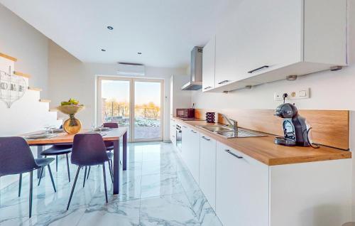 a kitchen with white cabinets and a table with purple chairs at Pet Friendly Home In Charnois With Wifi in Charnois