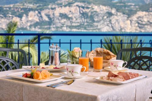 a table with plates of food and orange juice on it at Hotel Capri in Malcesine