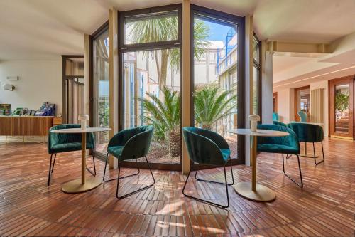 a lobby with green chairs and tables and windows at Hotel Capri in Malcesine