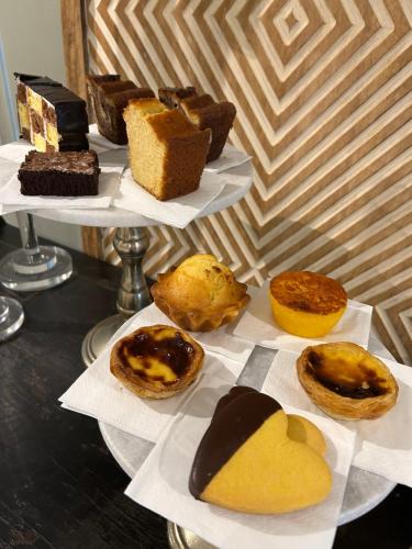 a group of different types of pastries on plates on a table at Arrábida Guest House in Setúbal