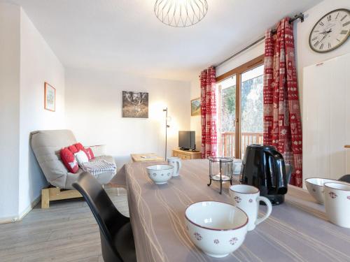 - un salon avec une table, des chaises et une horloge dans l'établissement Confort et Wifi gratuit : Appartement 3 pièces pour 4-6 personnes, proche pistes et remontées mécaniques - FR-1-265-307, à Modane