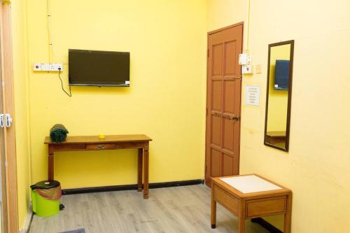 a room with a table and a television on a wall at Hotel & Homestay Four Friends Tanah Merah, Kelantan in Tanah Merah