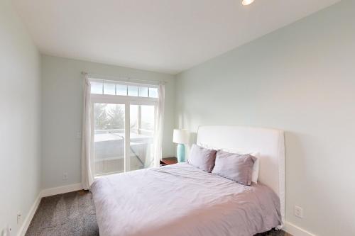 a white bedroom with a bed and a window at Alder Beach House in Oceanside