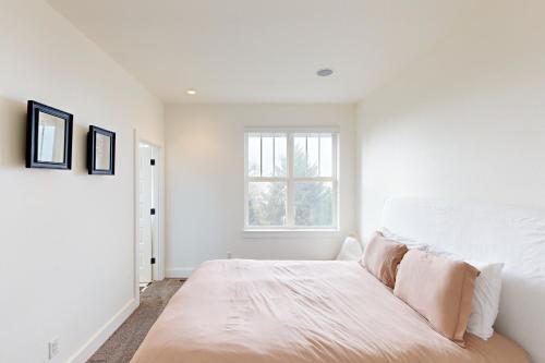 a white bedroom with a large bed and a window at Alder Beach House in Oceanside