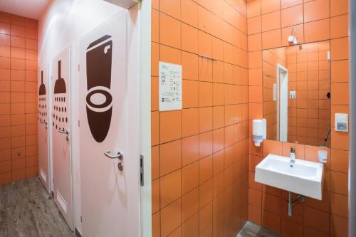 an orange bathroom with a sink and a mirror at Safestay Warsaw Old Town in Warsaw