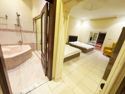 a bathroom with a tub and a bed and a sink at Hasy' House-You Jia in Jeddah