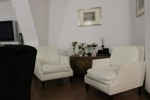 two white chairs and a television in a living room at Casa di fronte alle piste da sci campo da golf in Sestriere