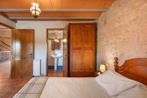 a bedroom with a bed and a stone wall at Cal Cirera in Sagás
