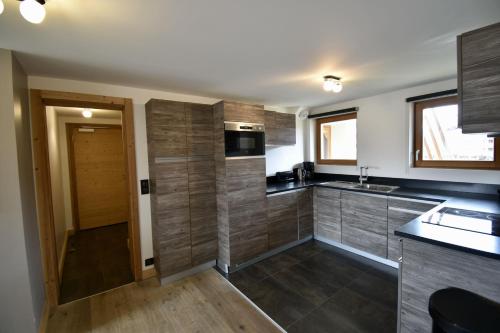 une cuisine avec des comptoirs noirs et des armoires en bois dans l'établissement Billy Avoriaz - Kouria 32, à Morzine