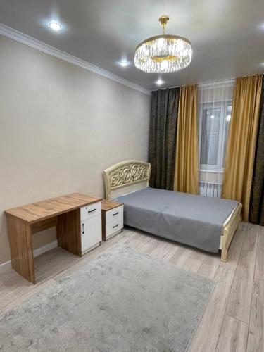 a bedroom with a bed and a desk and a chandelier at Apartments comfort new, Aktau 16 77 in Aktau