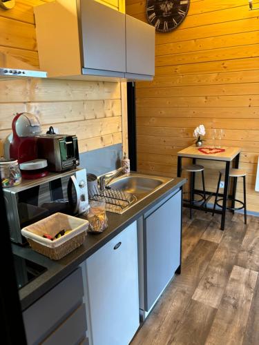 - une cuisine avec un évier et un comptoir avec une table dans l'établissement Chalet avec spa, Au Bois Quartois, à La Quarte