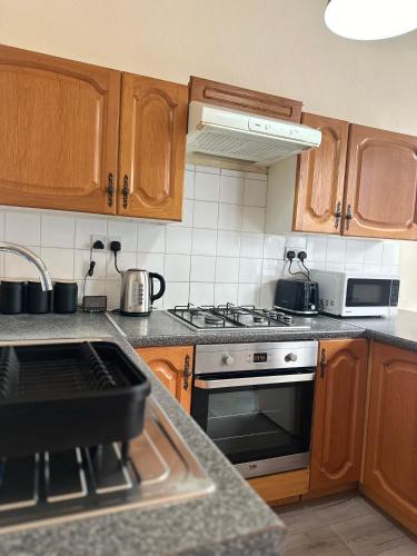 a kitchen with wooden cabinets and a stove top oven at 1 Bedroom Apartment By Guest Nest Management Vacation Rental Brighton - Pet-Friendly in Brighton & Hove