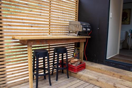 a wooden table with two bar stools in front of a wall at The Forest Dome Tsitsikamma in Stormsriviermond