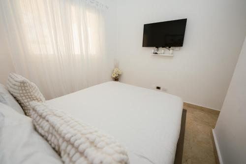 a bedroom with a white bed and a flat screen tv at Xeliter Cana Rock Punta Cana in Punta Cana