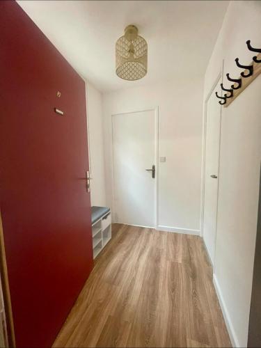 Cette chambre vide dispose d'une porte rouge et de parquet. dans l'établissement Cocon amiénois de standing, à Amiens