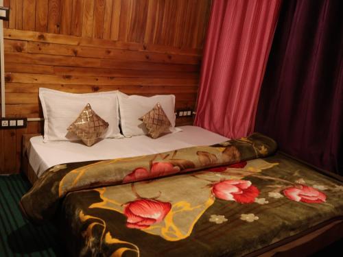 a bedroom with a bed with a flower blanket on it at Rustic wood house - A village home stay in Jibhi Valley in Jibhi