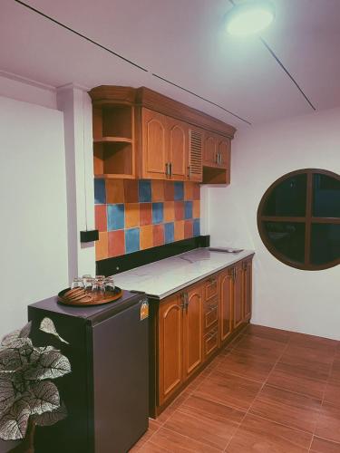 a kitchen with wooden cabinets and a black refrigerator at Aimei Bang Saray in Bang Sare