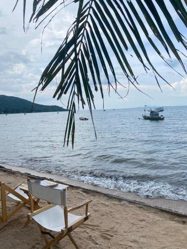 a beach with a chair and a boat in the water at Aimei Bang Saray in Bang Sare
