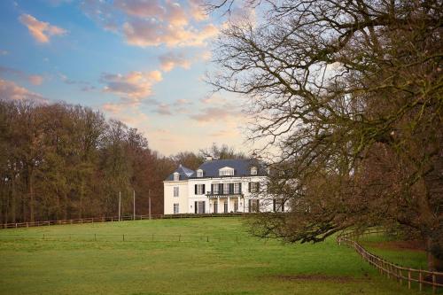 a large white house on a grassy field at Wellnessresort & Hotel De Valkenberg in Rheden