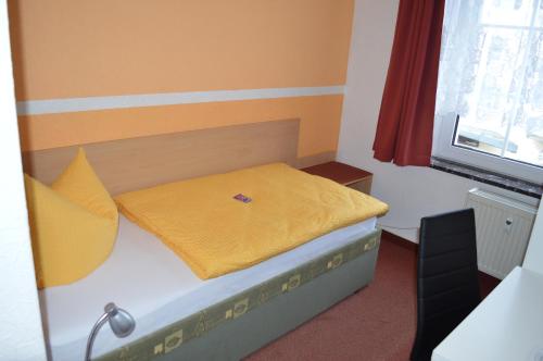 a small bedroom with a bed with yellow sheets and a window at Pension Tiffany in Chemnitz