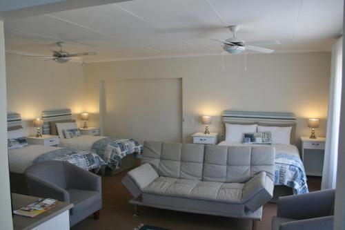 a hotel room with two beds and a couch and a chair at 113 on Robberg in Plettenberg Bay