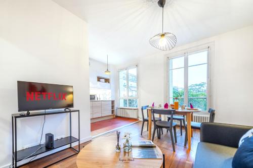een woonkamer met een tv en een tafel bij L'Escale Parisienne Charmant T2 proche métro et Paris in Pantin