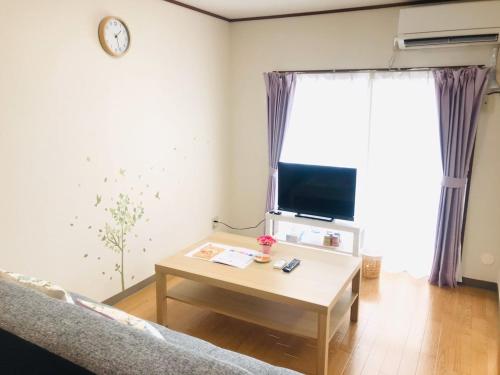 a living room with a coffee table and a tv at 桜並木と航空公園の近くにある閑静なお部屋 最大5名 t10 in Tokorozawa